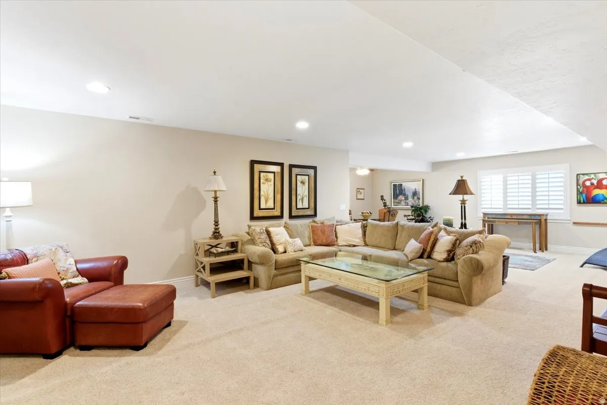 Spacious carpeted room featuring recessed lighting and a window with plantation shutters