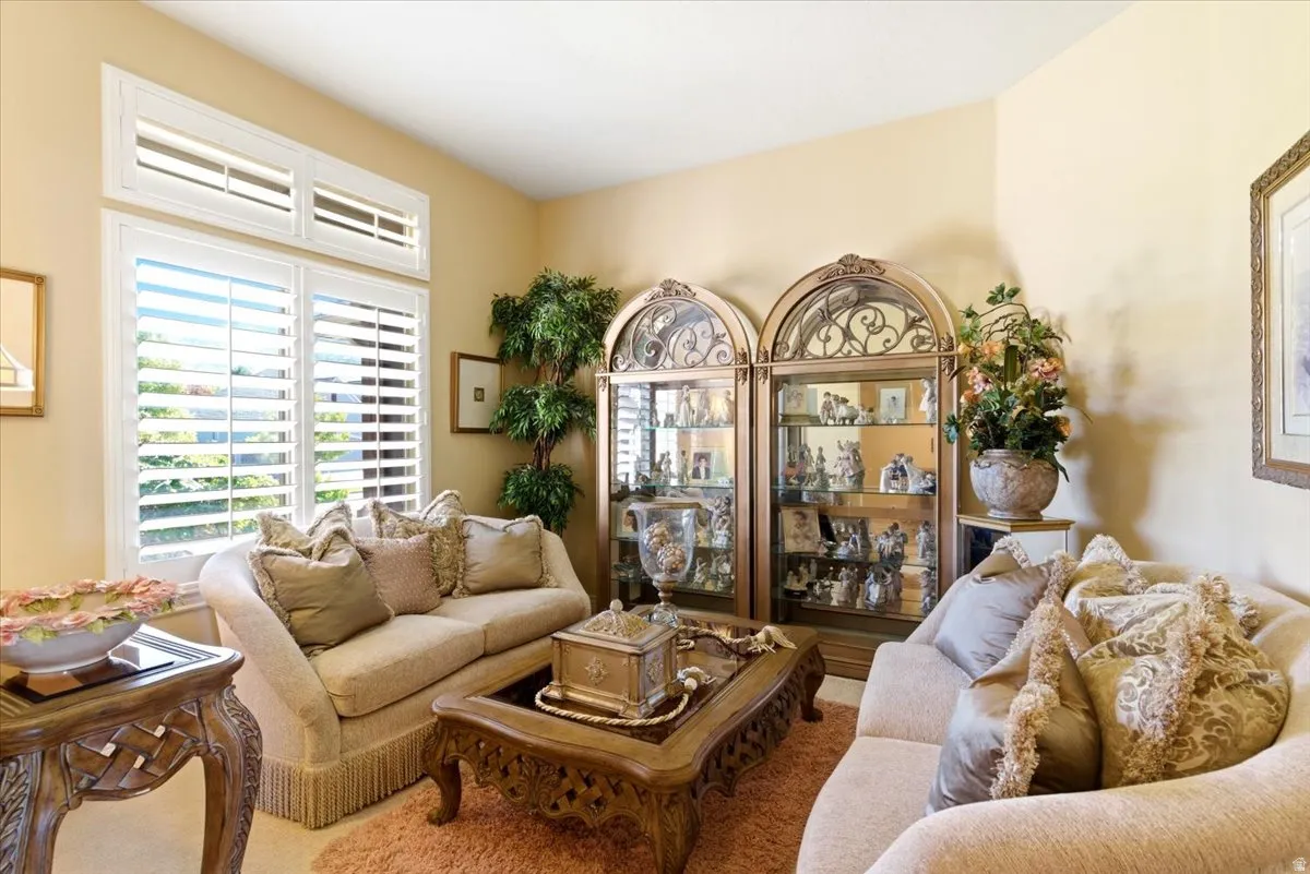 Room featuring a large window with plantation shutters, two arched glass-front display cabinets, and neutral wall paint