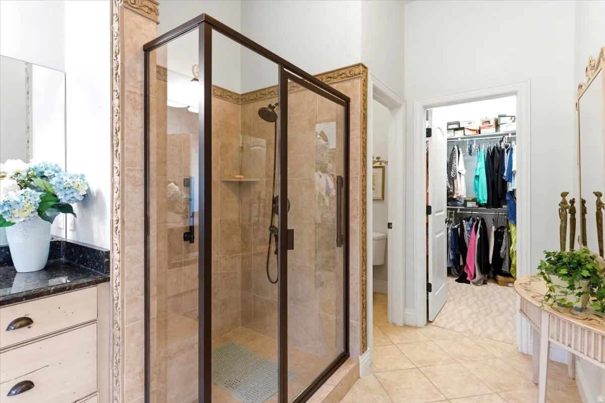 Walk-in shower with bronze-finish frame and showerhead, complemented by a tile surround