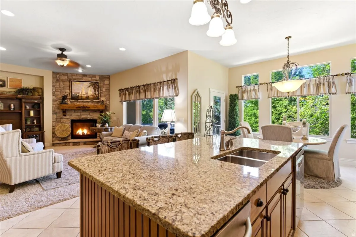 Open-concept kitchen and living area featuring an island with a double basin sink and stone-finish countertop