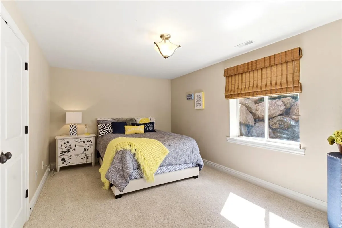 Bedroom featuring neutral wall paint, carpet flooring, a window with a woven wood shade, white baseboards, and a ceiling-mounted light fixture