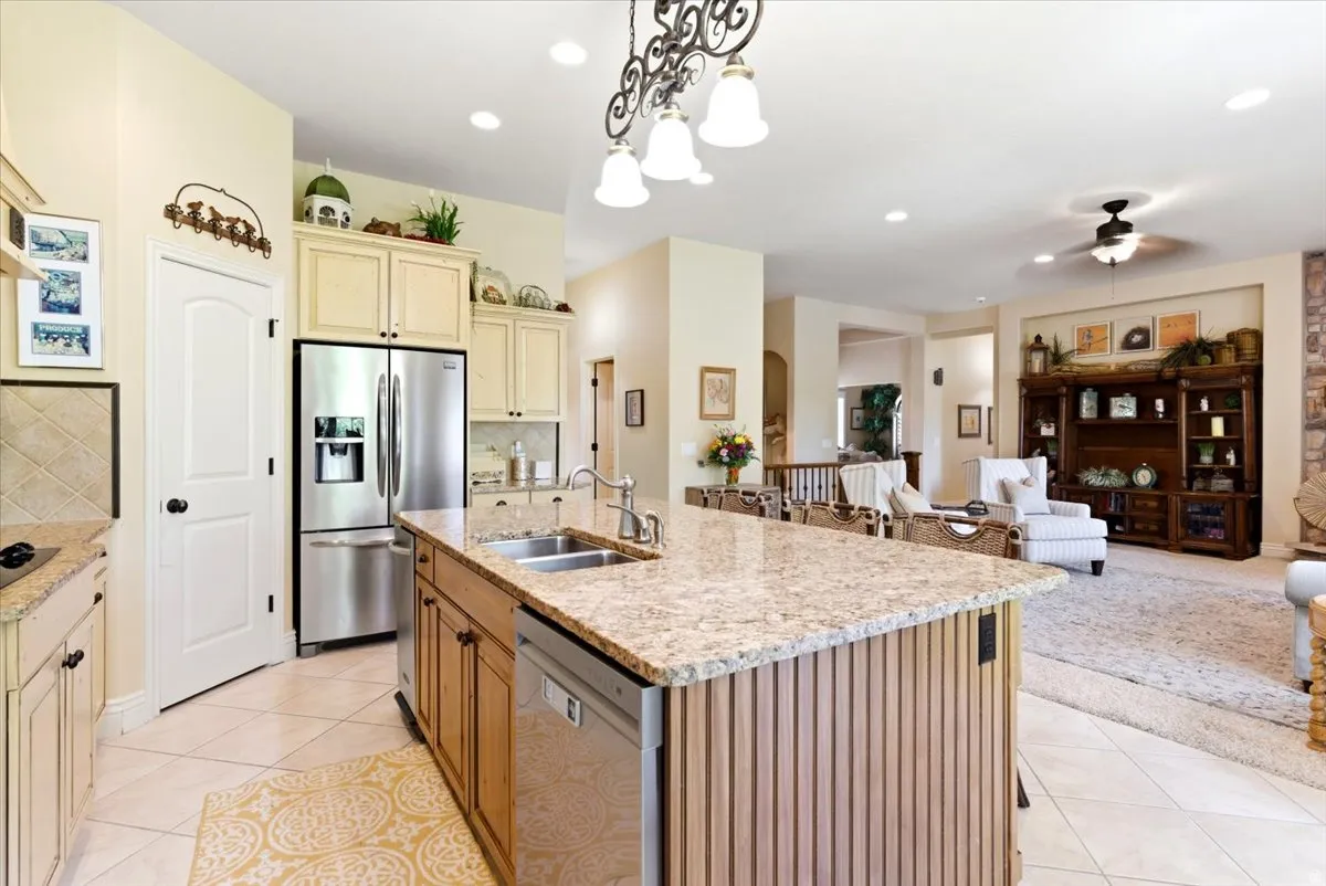 Spacious kitchen with a large island featuring dual sinks, granite countertops, tile flooring, and integrated stainless steel appliances