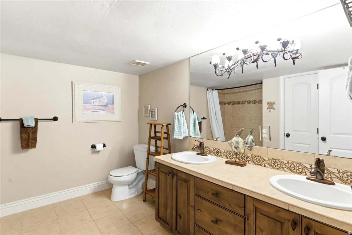 Bathroom featuring a dual vanity with integrated sinks, wood cabinetry, and a full-width mirror