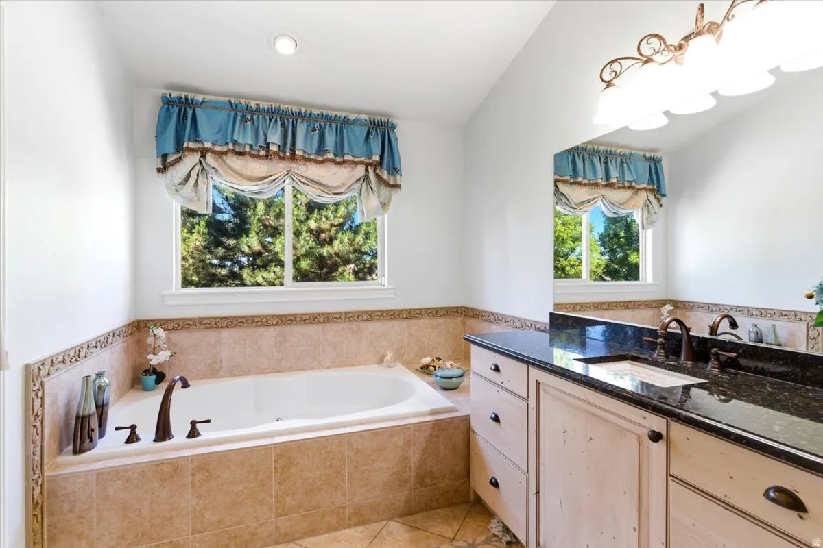 Built-in garden tub with bronze fixtures set in neutral-toned tile surround