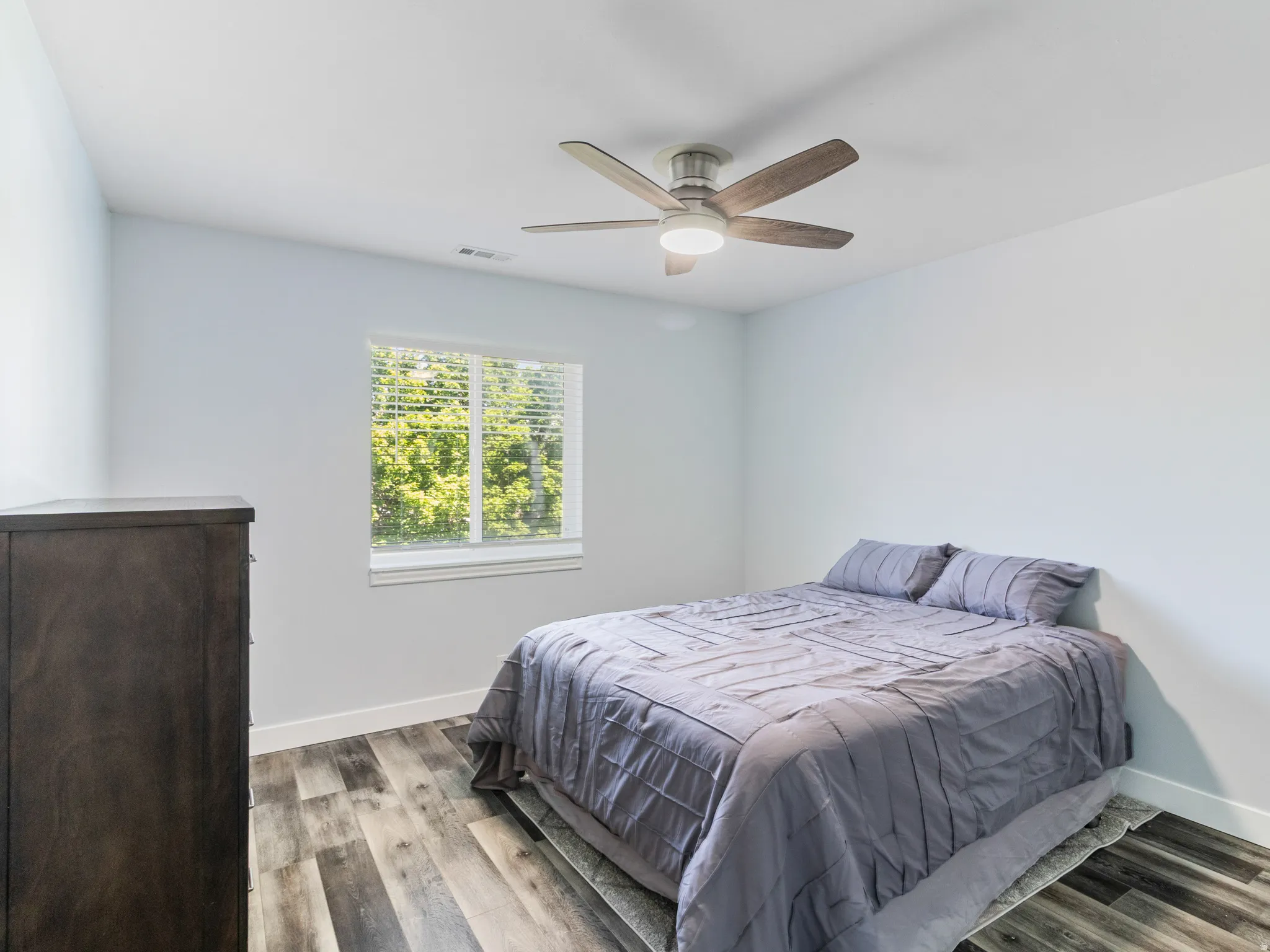 Bedroom 2 with wood-finish flooring, a window with blinds, and a ceiling fan with integrated lighting