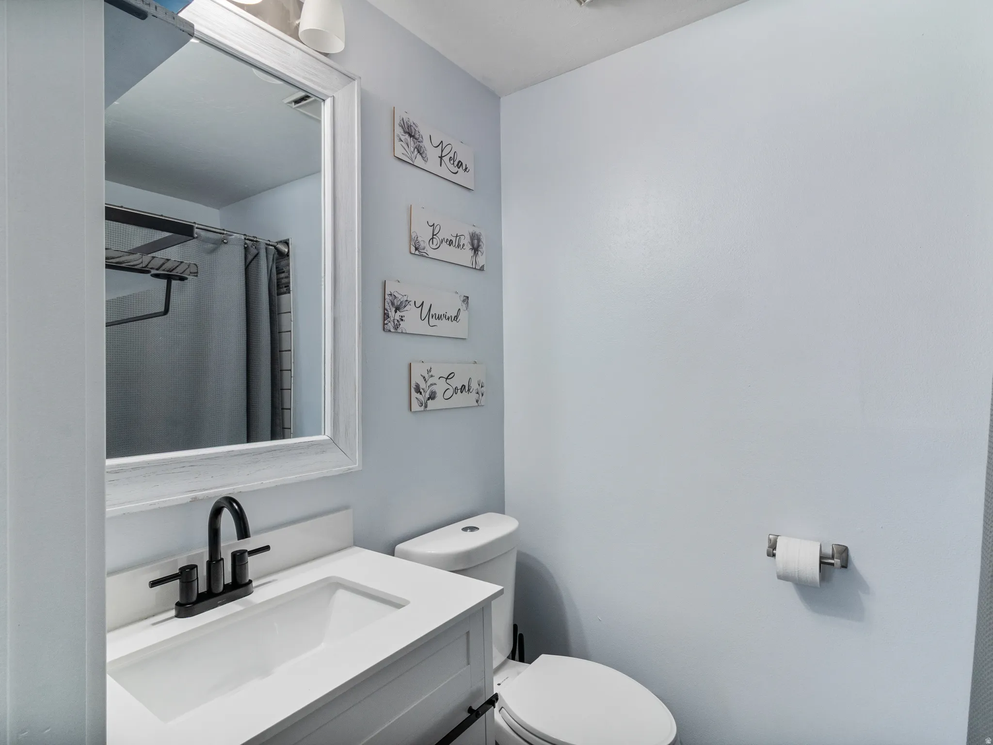 Primary Bathroom featuring a white vanity with an integrated sink, matte black faucet, and a large framed mirror
