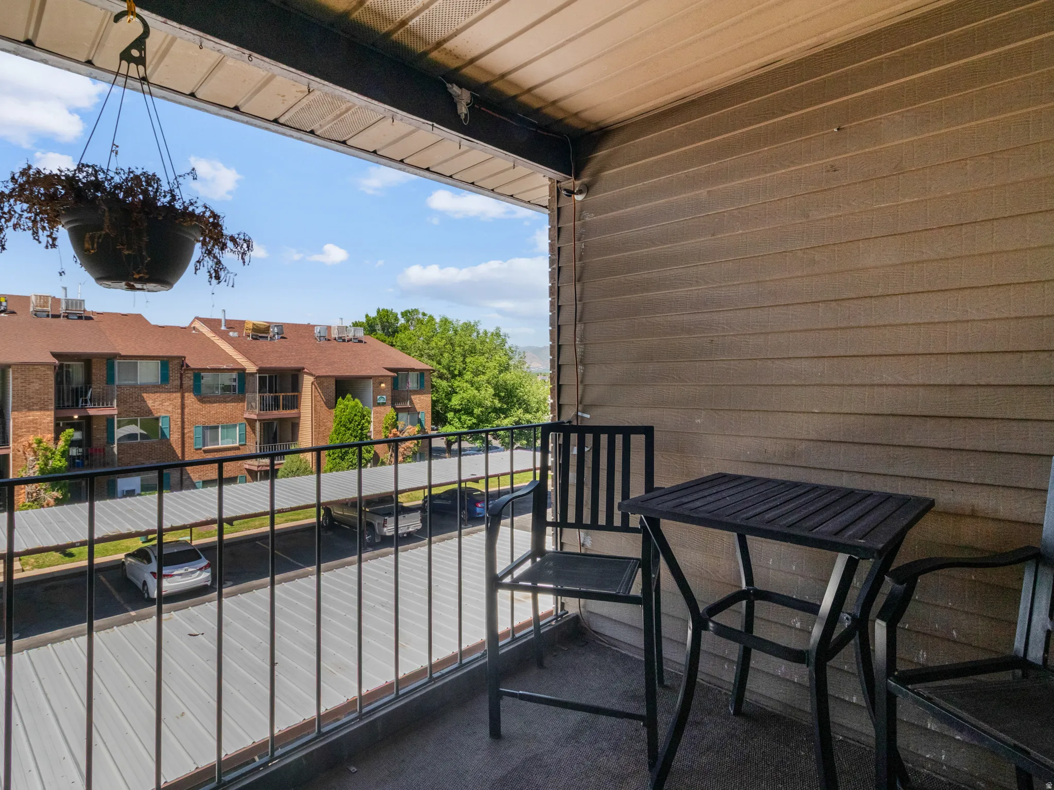 Covered balcony with a textured ceiling, horizontal siding, and a black metal railing