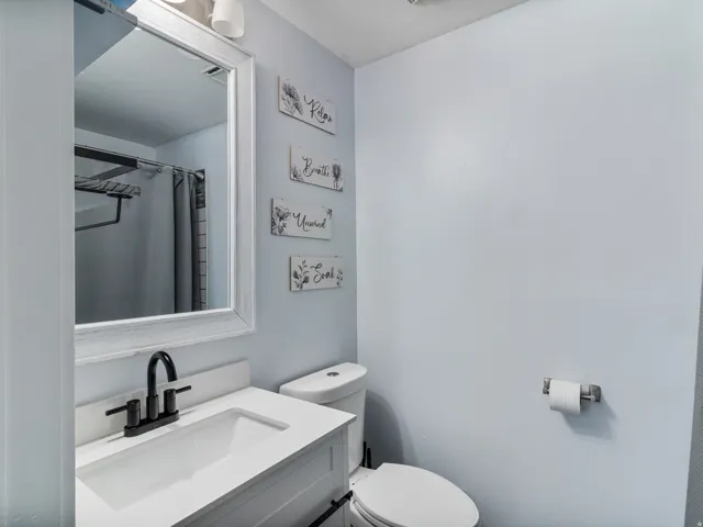 Primary Bathroom featuring a white vanity with an integrated sink, matte black faucet, and a large framed mirror