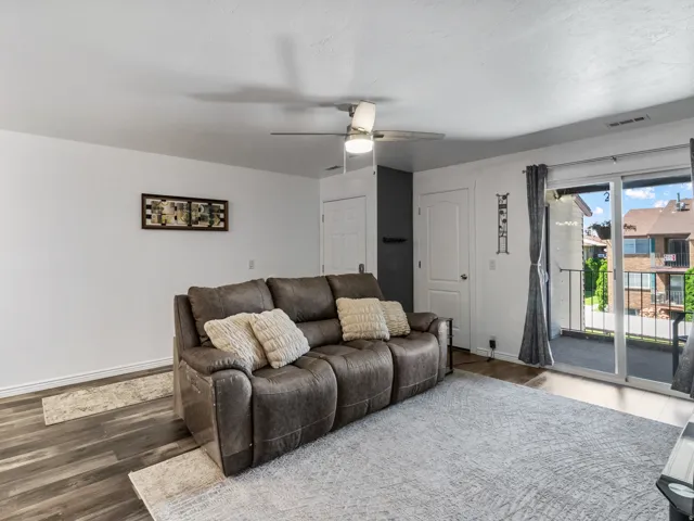 Living area with wood-finish flooring, white walls, and a ceiling fan