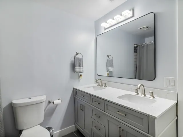Dual sink vanity with a white countertop, brushed nickel fixtures, and a large framed mirror
