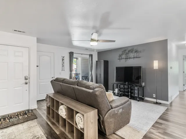 Welcome to your new home! Open living area featuring wood-finish flooring, a ceiling fan with integrated lighting, and a neutral color palette