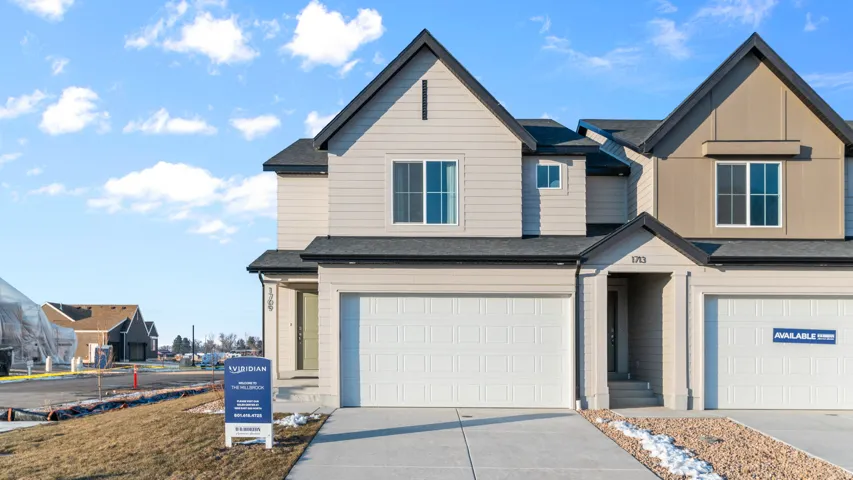 Contemporary townhouse exterior featuring a neutral color palette, dark shingle roofing, attached two-car garage, and a concrete driveway