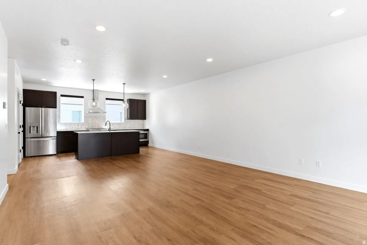 Open-concept living area featuring wood-finish flooring, recessed lighting, and a modern kitchen