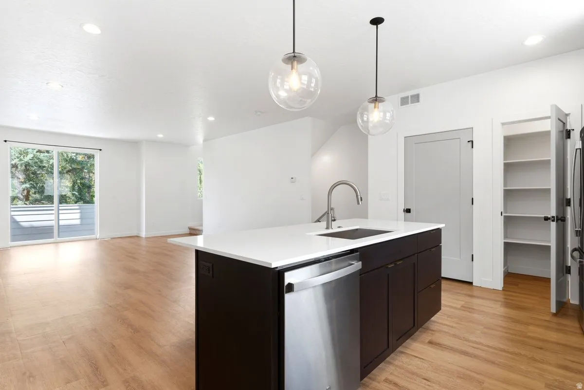 Modern kitchen island featuring a stainless steel sink, gooseneck faucet, and integrated dishwasher