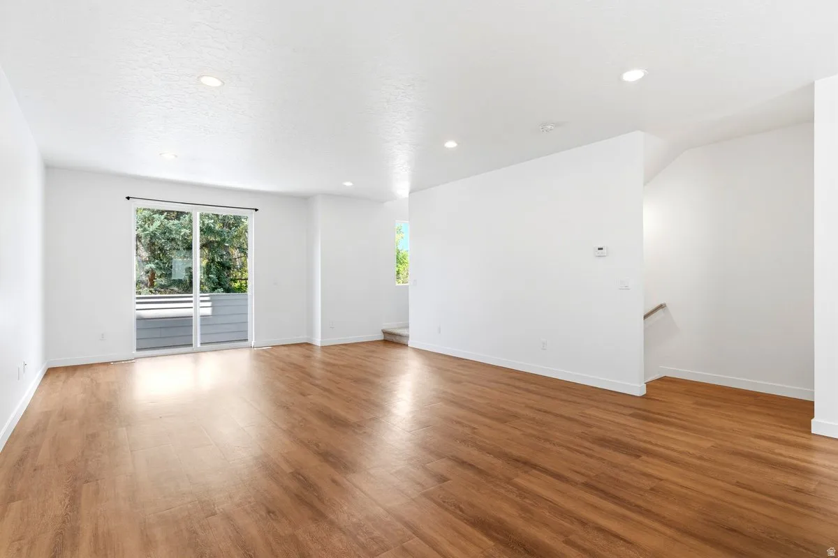 Open-concept living space featuring wood-finish flooring, recessed lighting, and white walls