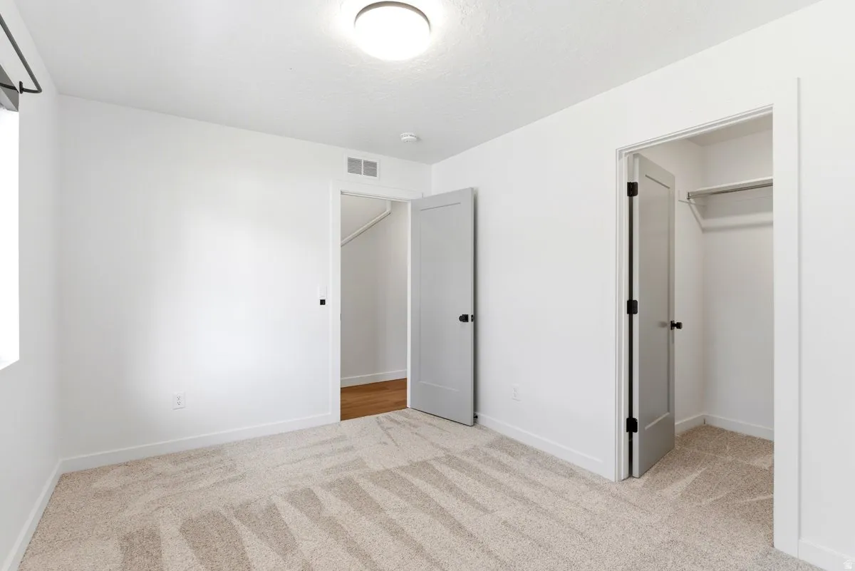 Neutral-toned wall-to-wall carpeting complements bright white walls and trim