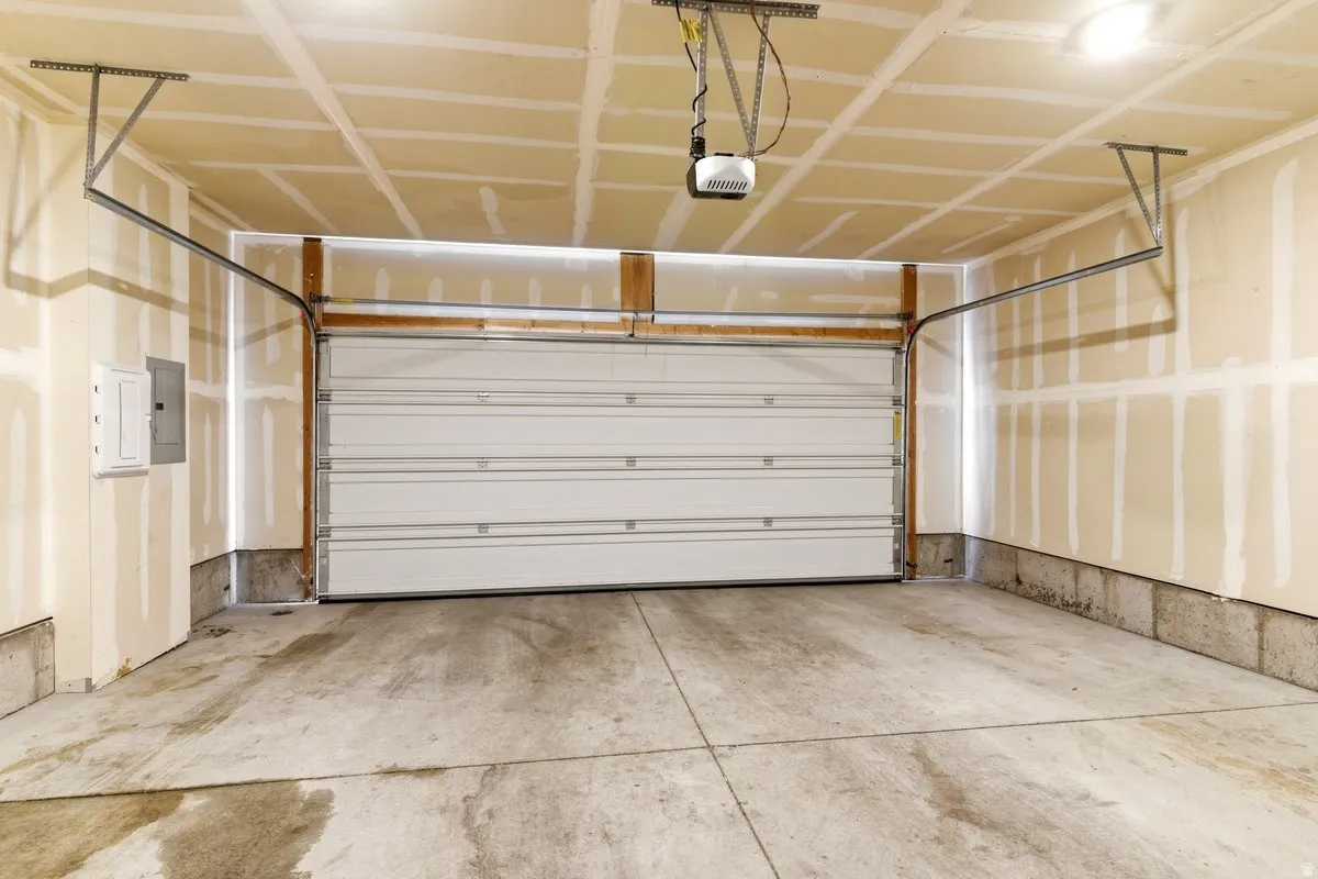 Spacious garage featuring a concrete floor, overhead lighting, and an automatic garage door opener