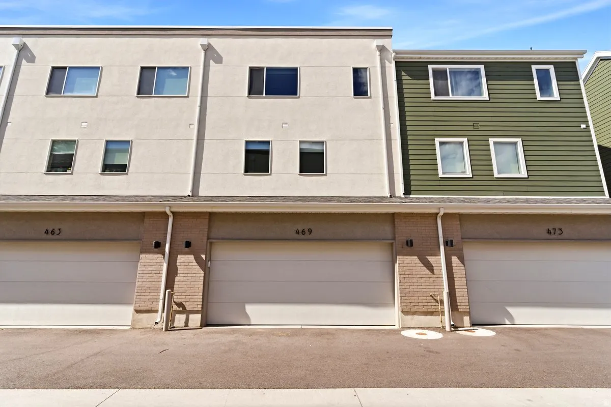 Contemporary townhome facade featuring a neutral stucco finish and green horizontal siding