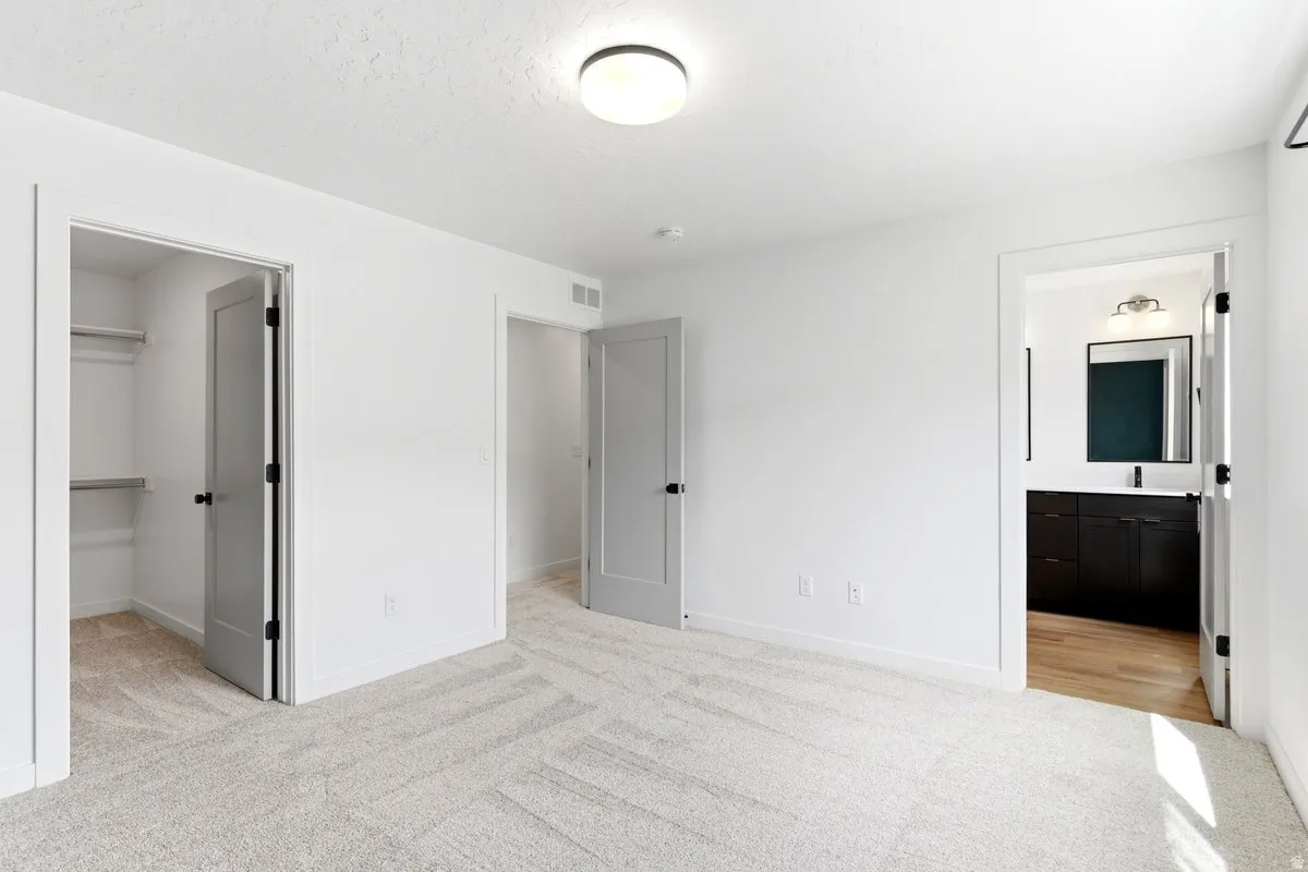 Spacious room featuring light-toned carpet flooring and white walls