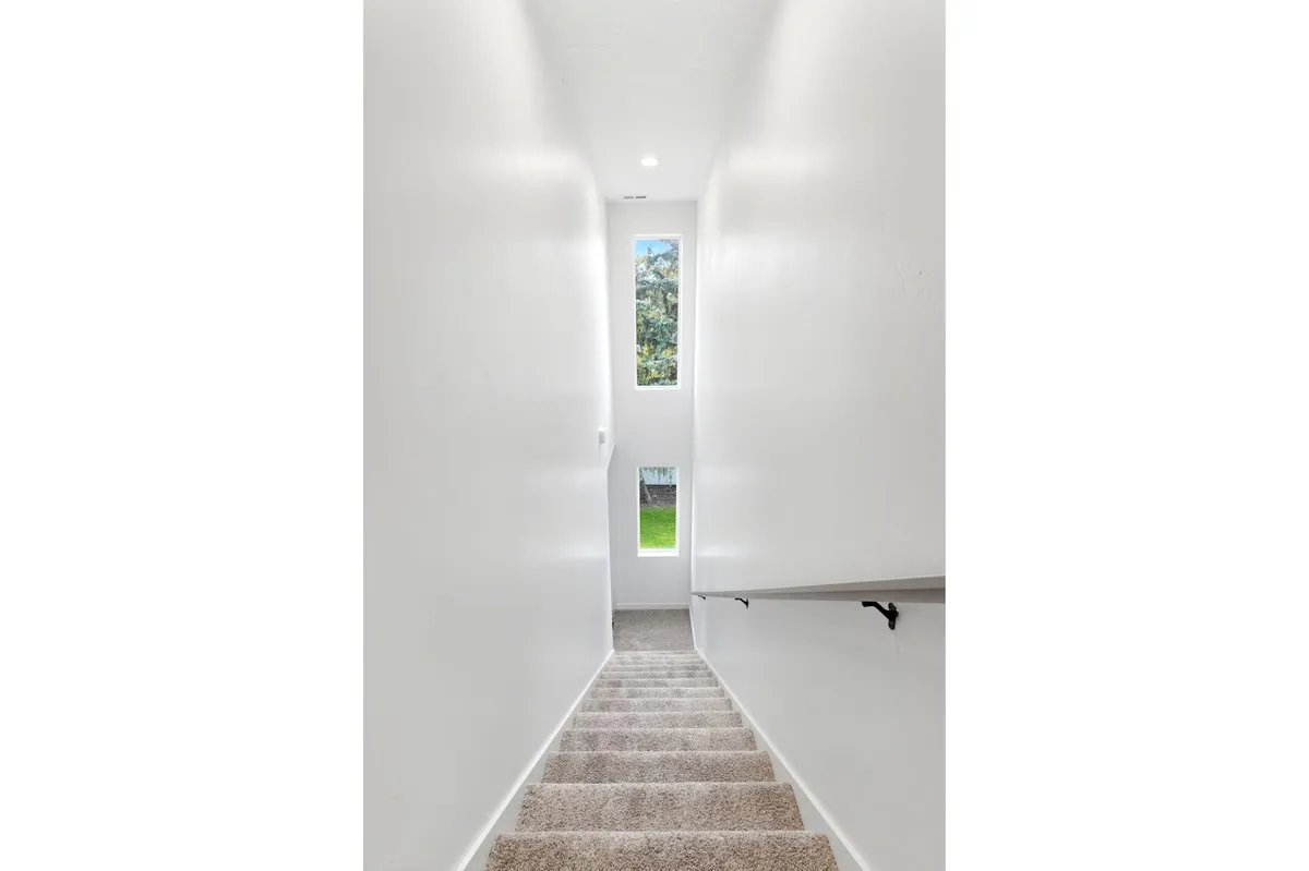Staircase with carpeted treads and a light-colored railing