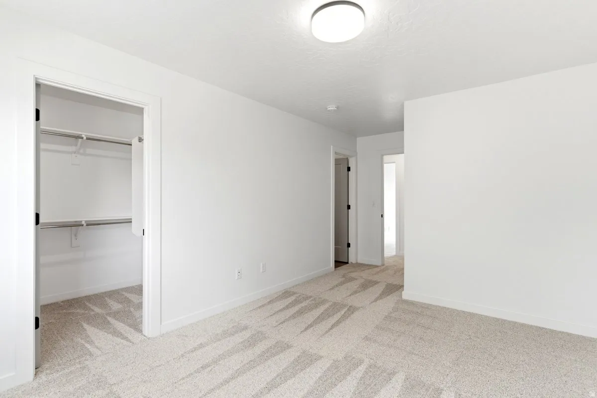 Spacious room featuring light-toned patterned carpet and crisp white walls