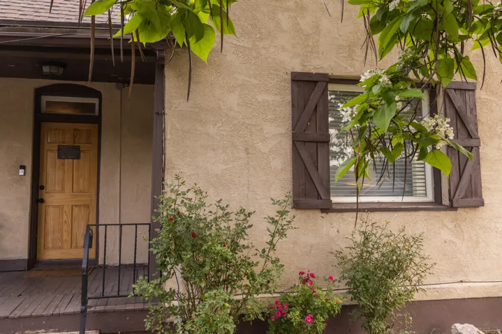 Stucco exterior with a natural wood-panel entry door, transom window, and dark trim