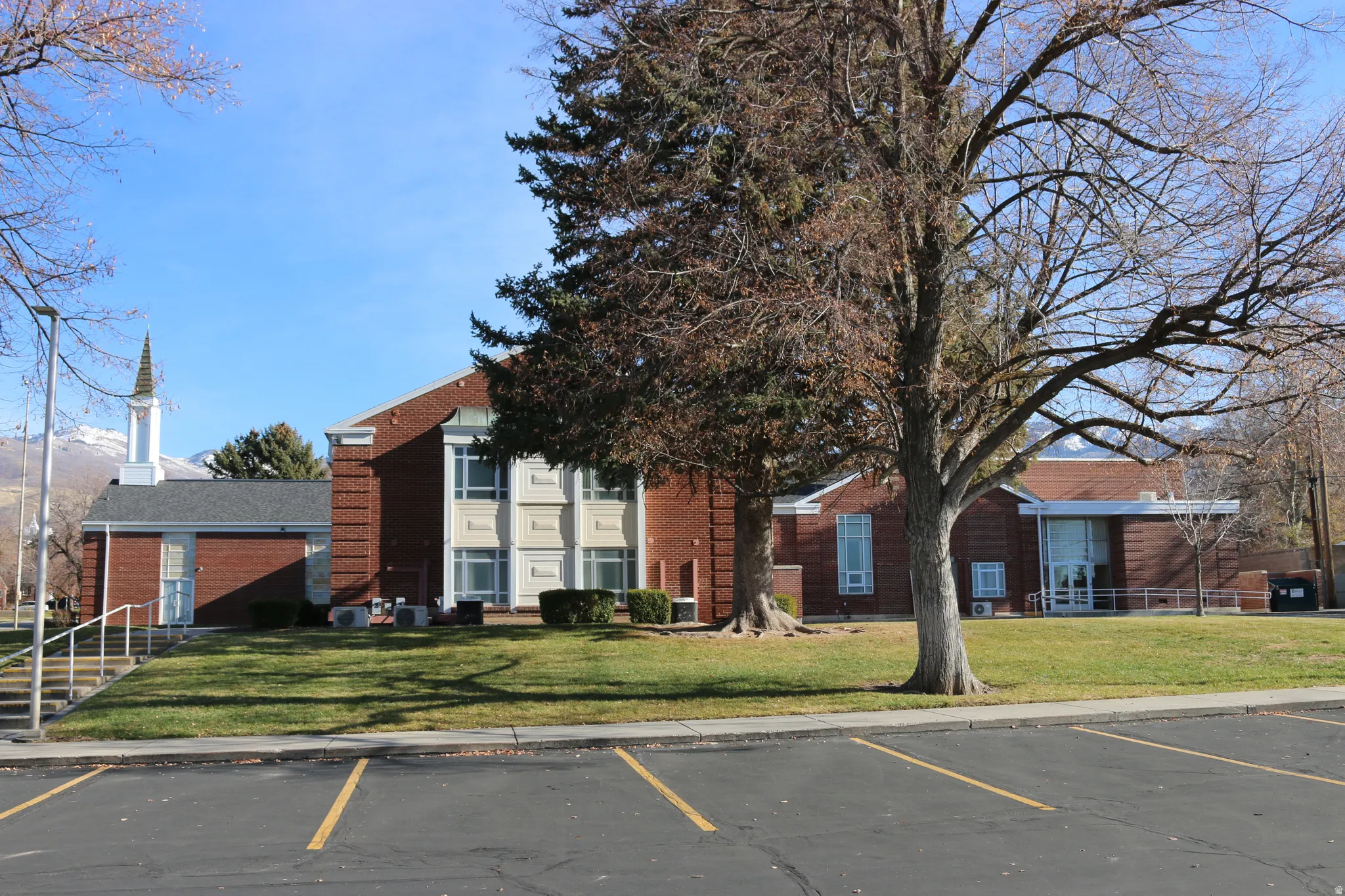 Brick exterior building featuring multiple architectural styles and a prominent steeple.