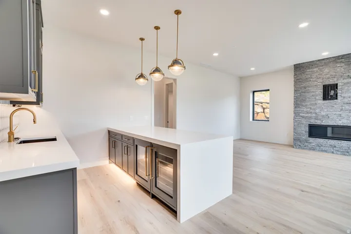 Modern wet bar featuring matte gray cabinetry, white countertops, a gold-finish faucet, and integrated beverage coolers