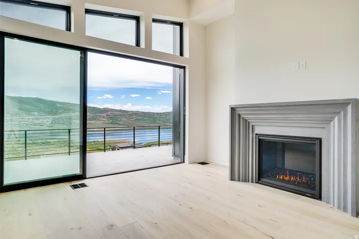 Spacious room featuring light wood-finish flooring, a modern fireplace with a tiered surround, and expansive sliding glass doors