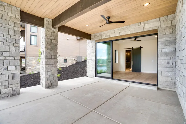 Covered patio featuring stone columns and a paneled wood-finish ceiling with recessed lighting and a ceiling fan