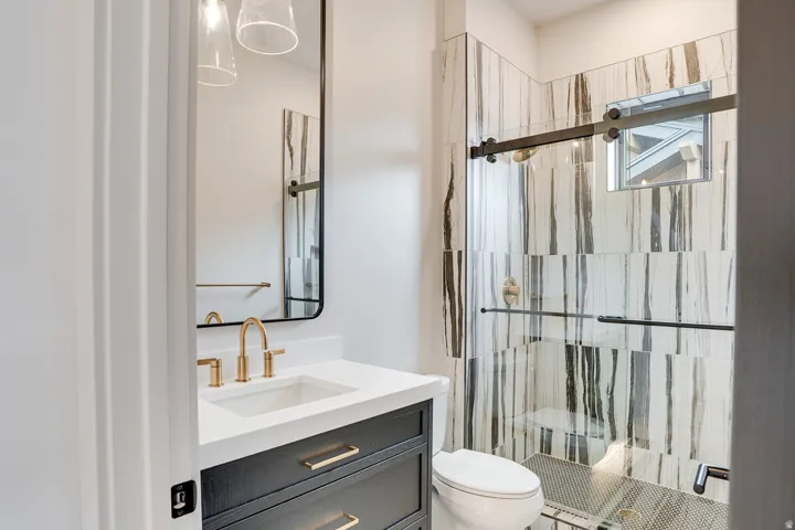 Bathroom featuring a dark wood vanity with gold-tone hardware, white countertop, and gold-tone faucet