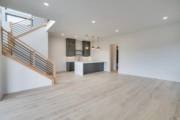 Spacious open-concept area featuring light wood-finish flooring and recessed lighting