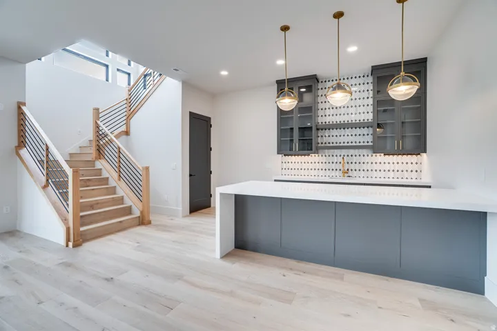 Custom wet bar featuring dark gray cabinetry, white countertop, and patterned tile backsplash