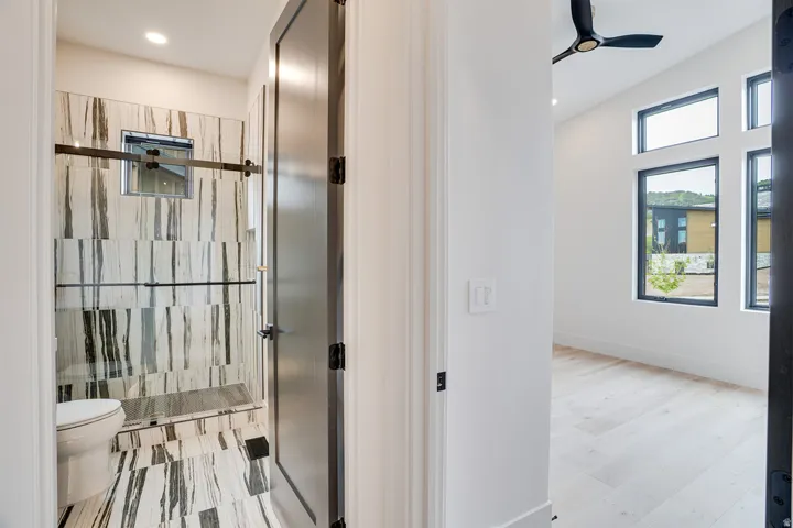 Shower with glass enclosure, integrated bench, and black and white striped tile flooring and walls