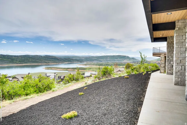 Exterior stone facade with wood-finish soffit, recessed lighting, and a concrete pathway