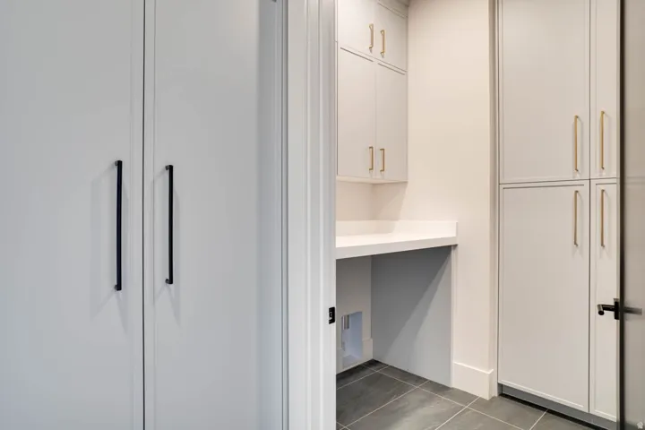 Utility area featuring extensive built-in cabinetry, solid surface countertop, and dark gray tile flooring