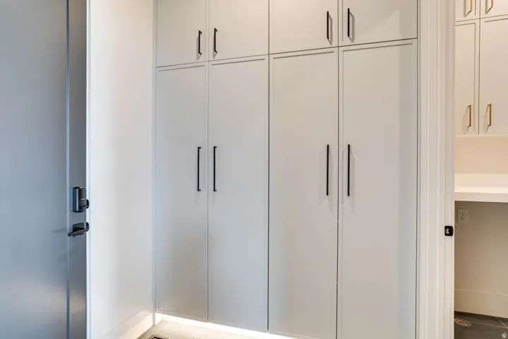 Built-in cabinetry with black hardware, under-cabinet lighting, and a modern door with smart lock feature