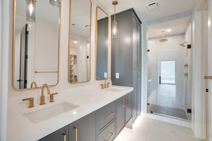 Double vanity with integrated sinks, brushed gold fixtures, and custom cabinetry