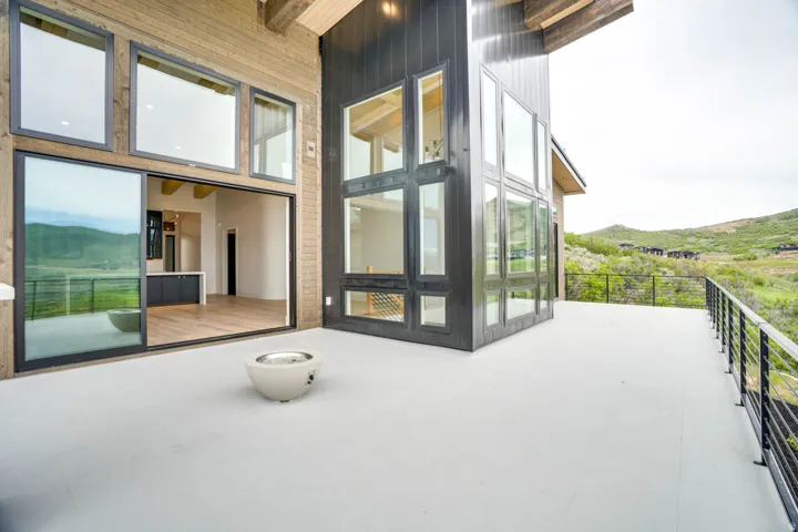 Expansive exterior patio featuring a concrete surface, black metal railing, and a modern fire bowl