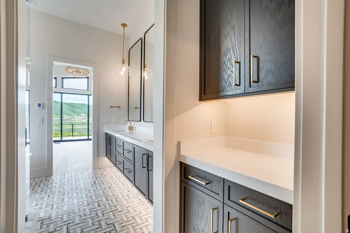 Modern bathroom featuring a dual vanity with dark wood-finish cabinetry, white countertops, and gold-finish fixtures