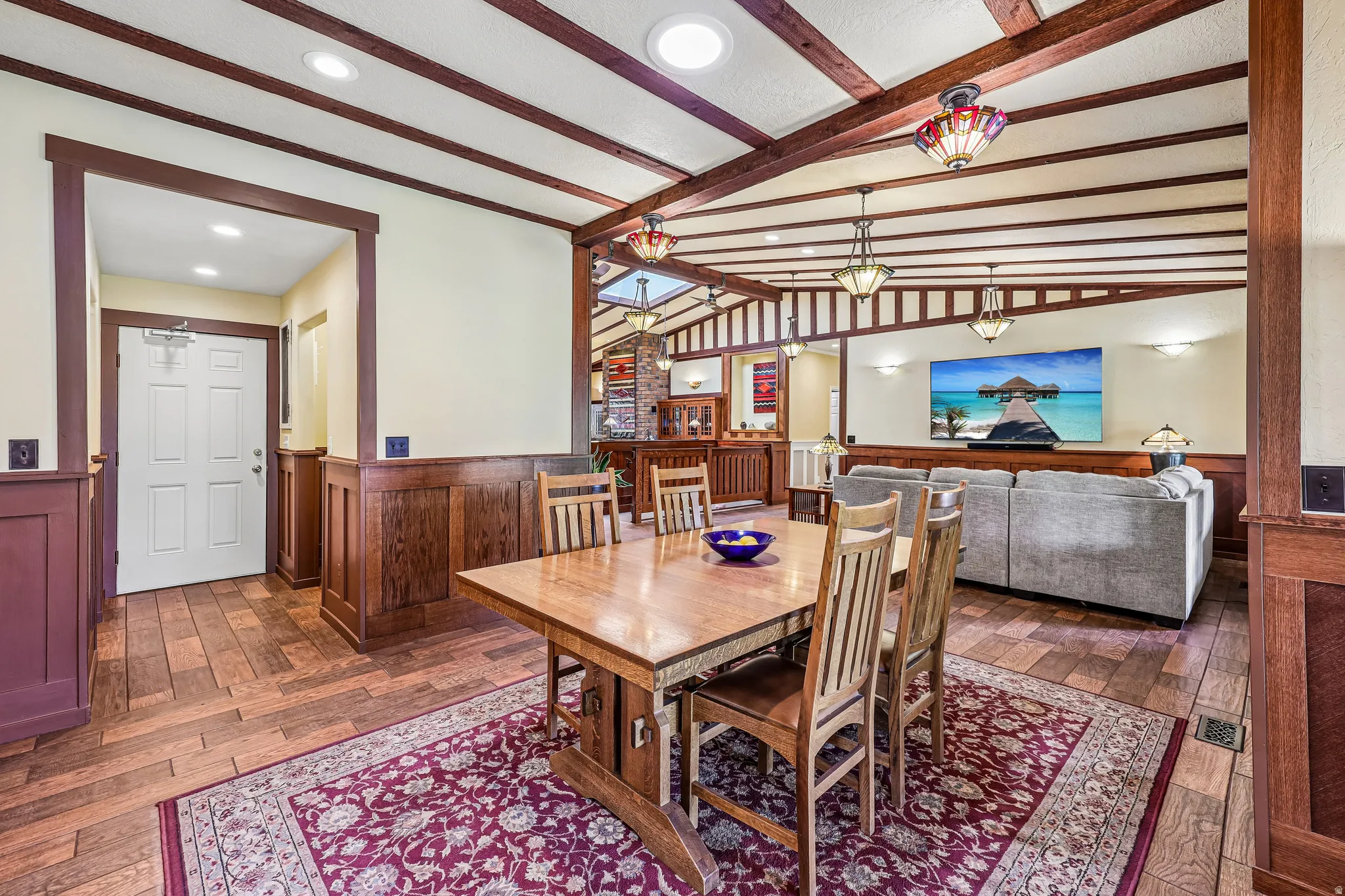 Open-concept living space with exposed wood ceiling beams, recessed lighting, and wood-finish flooring
