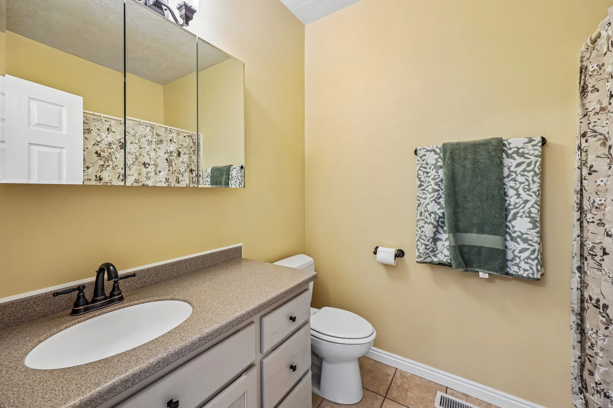 Bathroom with a light brown-speckled countertop, undermount oval sink, and oil-rubbed bronze faucet