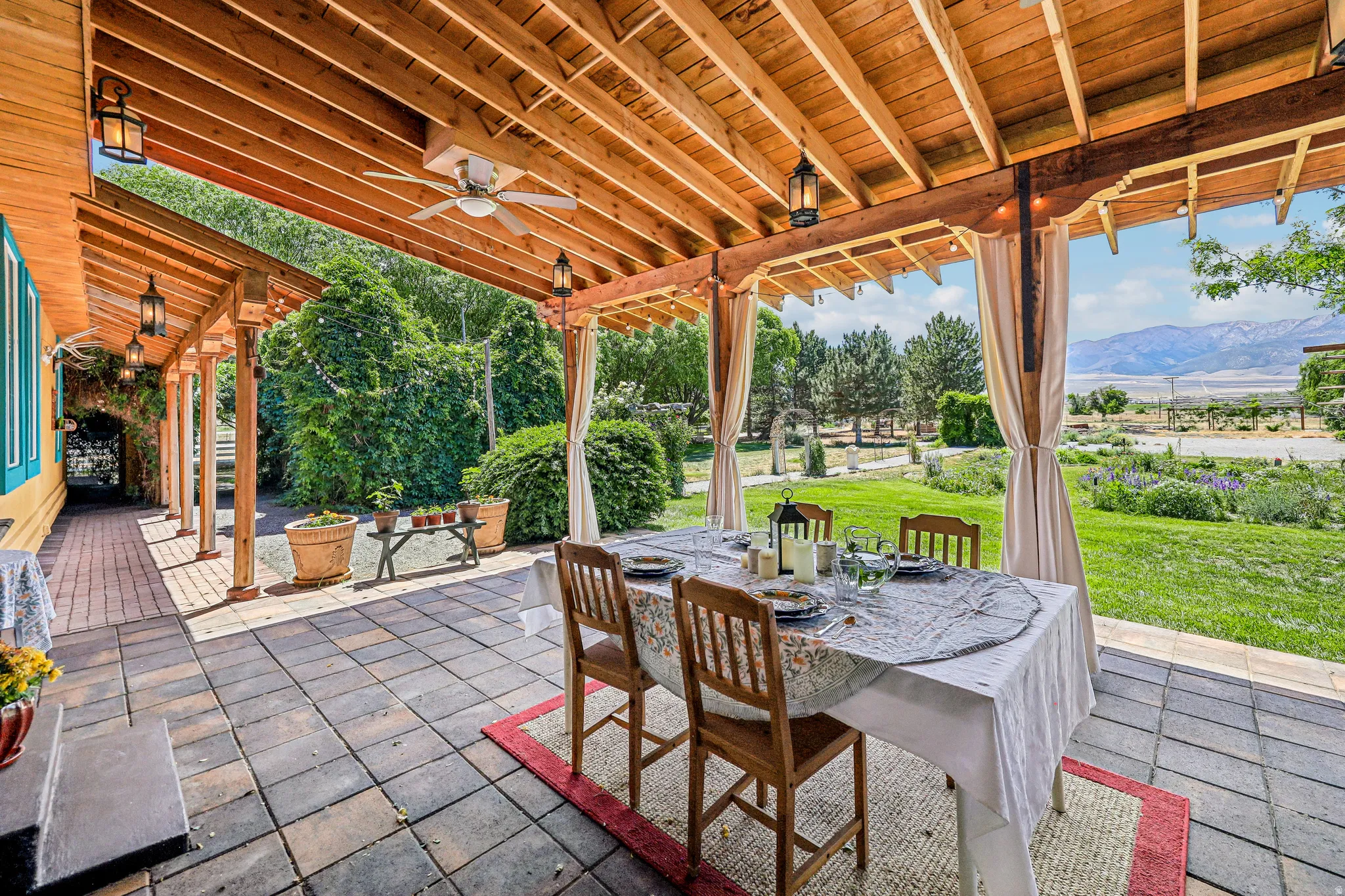 Expansive covered patio featuring a wood beam ceiling, ceiling fan, and decorative lanterns