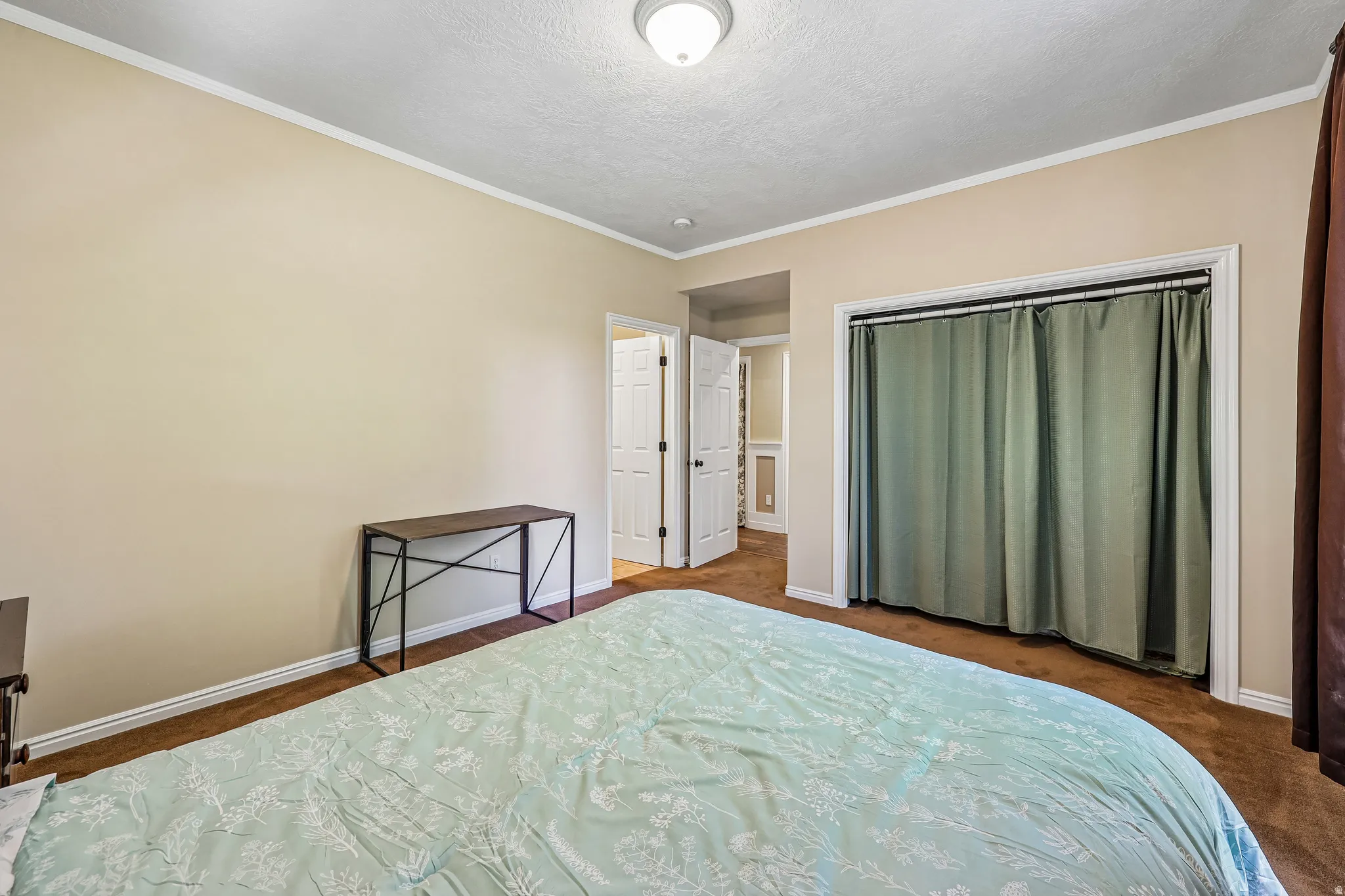 Bedroom featuring neutral-toned walls, crown molding, and textured ceiling