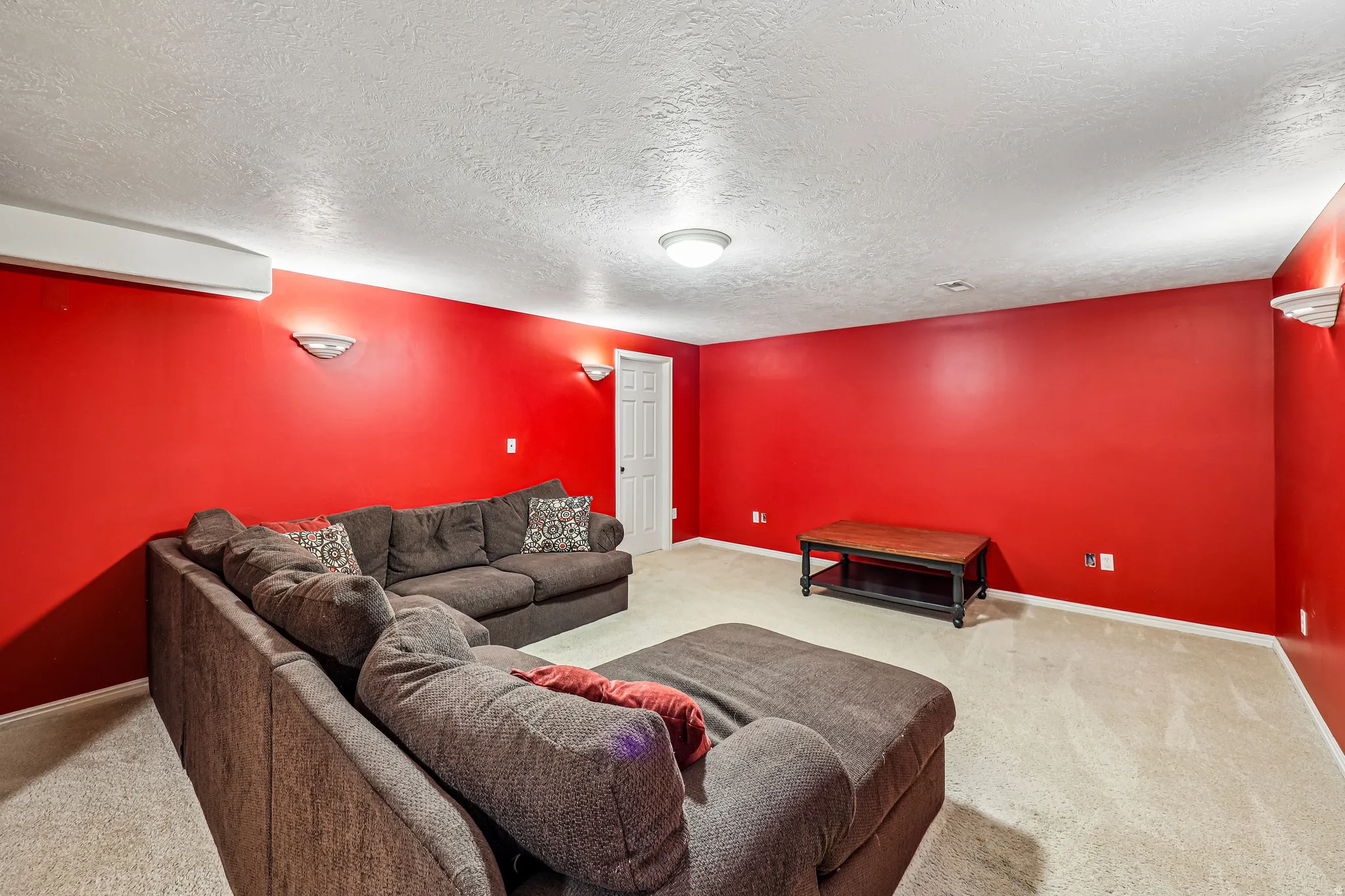 Spacious room featuring broad red walls, light-colored carpeting, a white ceiling, and a white interior door