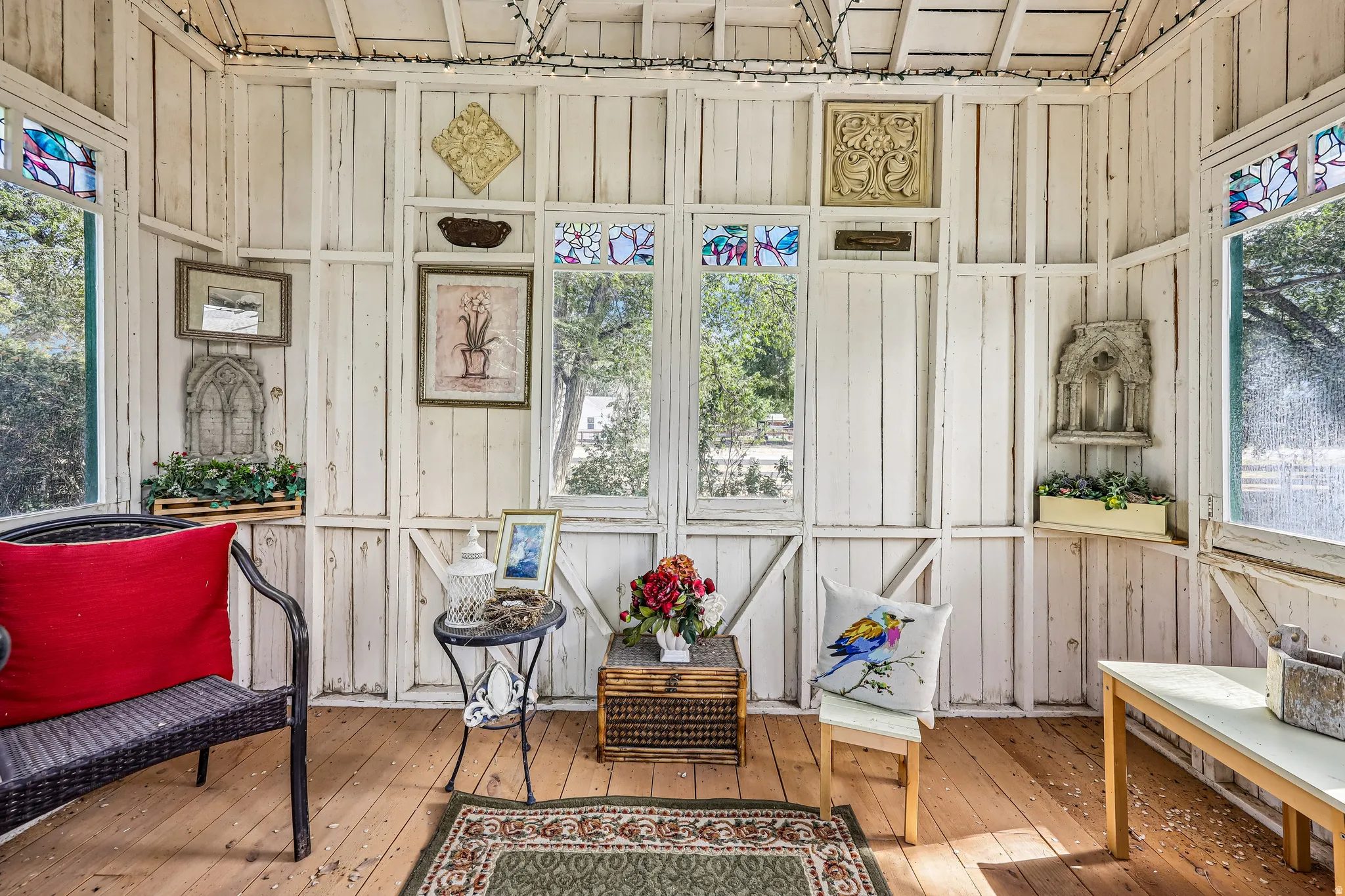 Sunroom featuring painted wood panel walls, wood-finish flooring, multiple windows, and decorative stained-glass accents