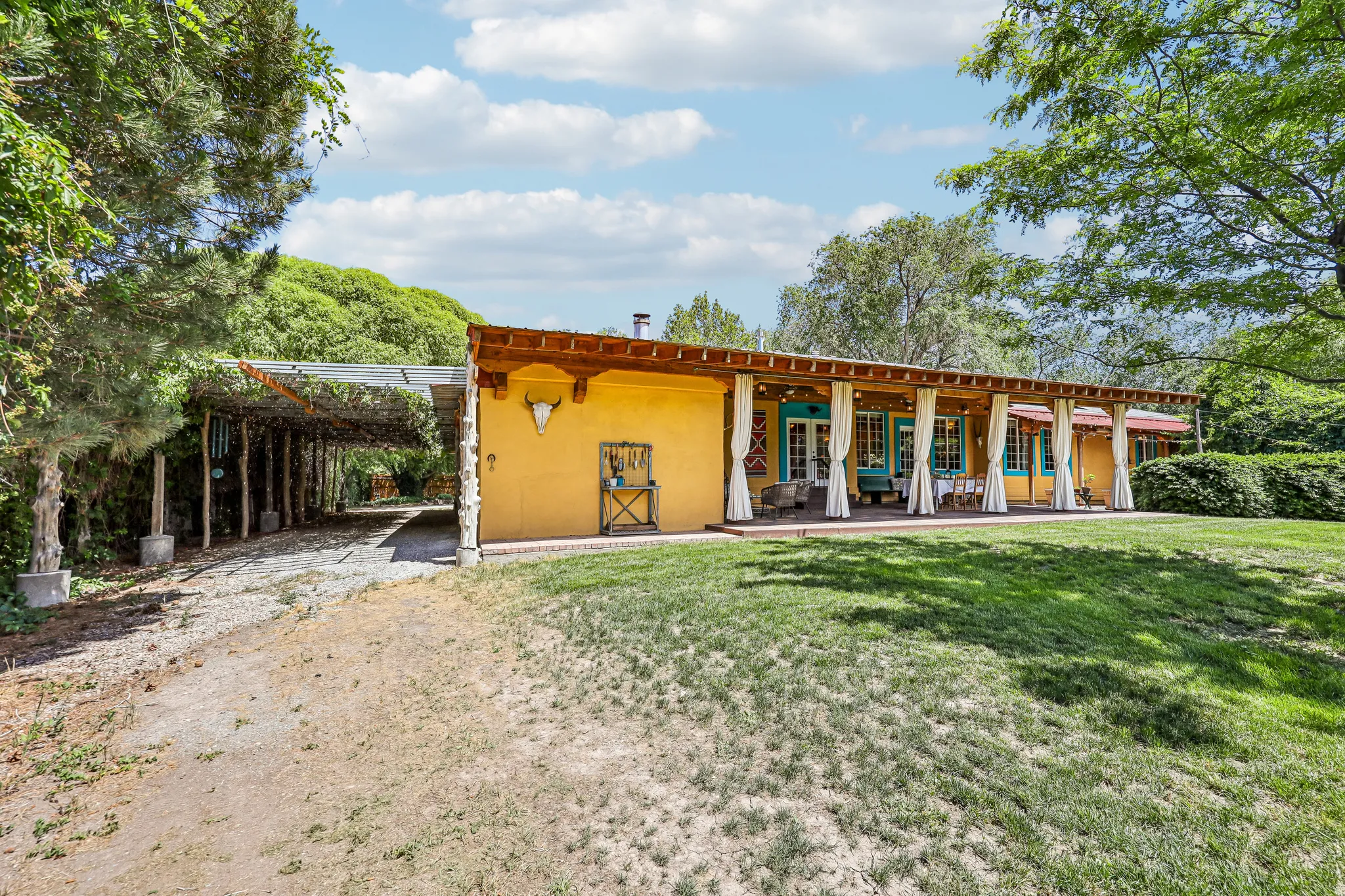 Exterior featuring yellow stucco, a covered carport, and an extended covered patio