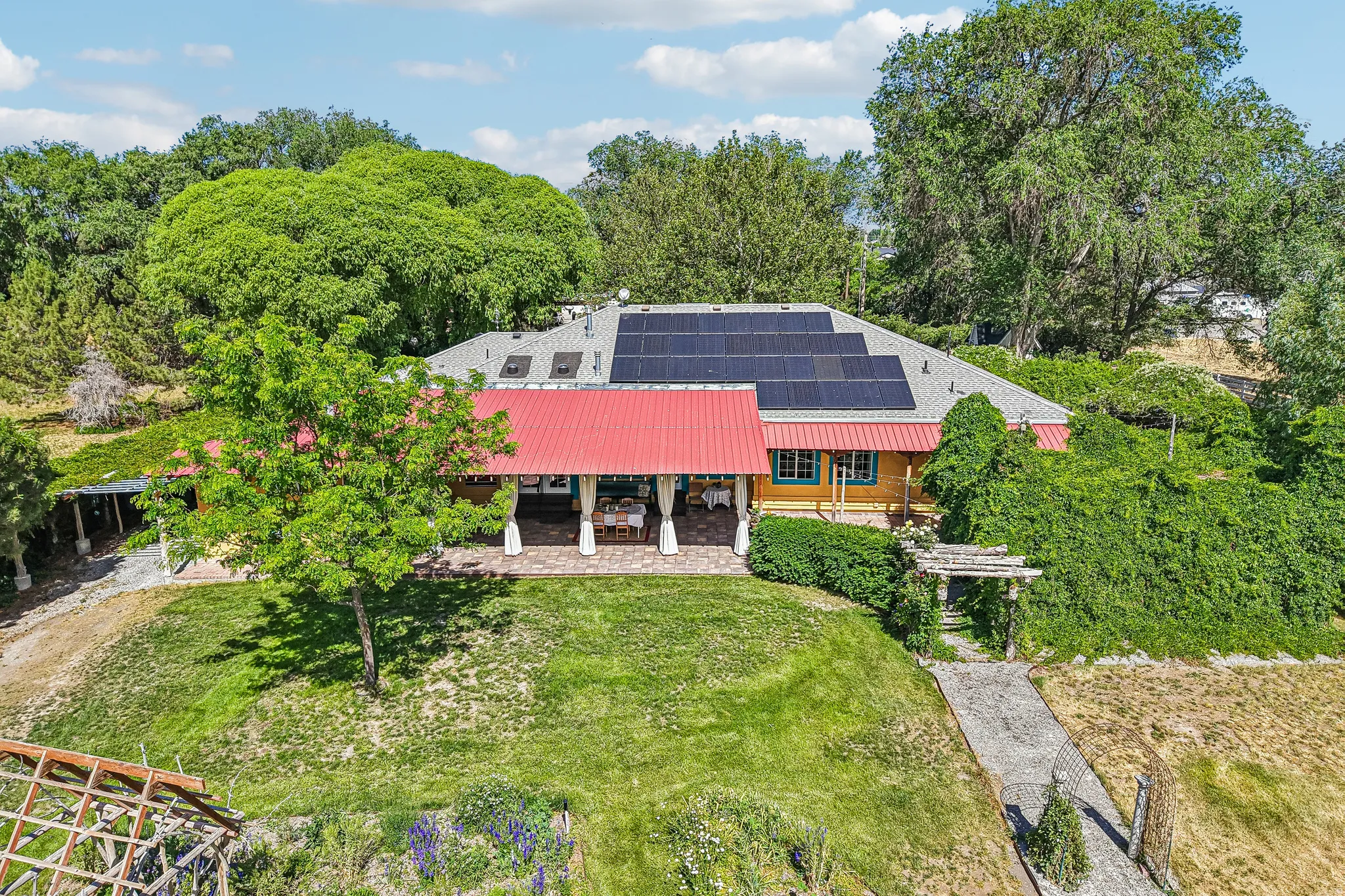 Ranch-style exterior with a red metal roof and solar panel array