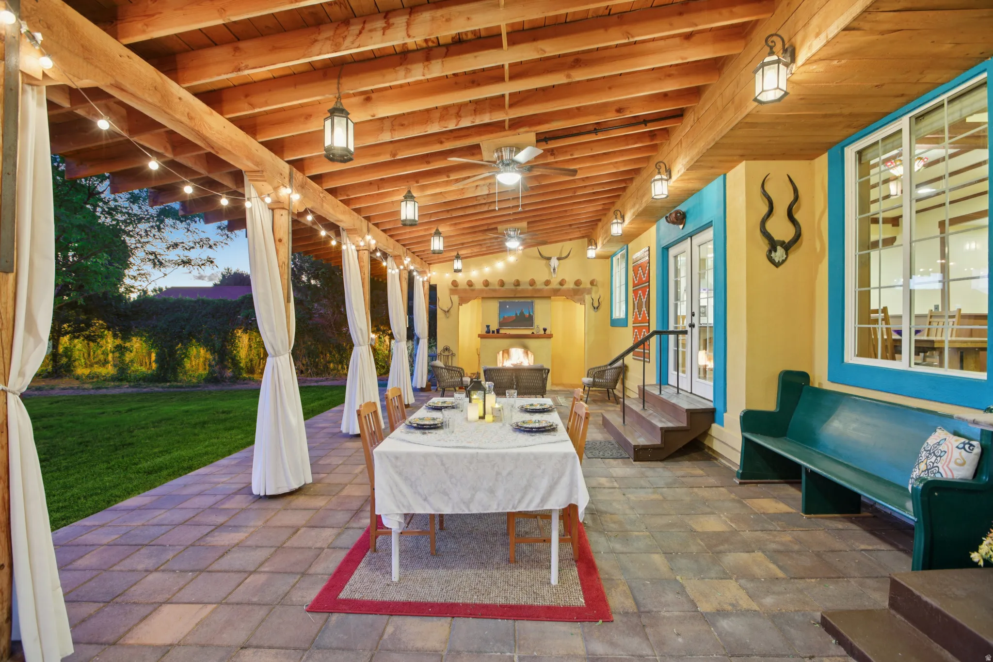 Expansive covered patio featuring a wood-beam ceiling, string lighting, and ceiling fans
