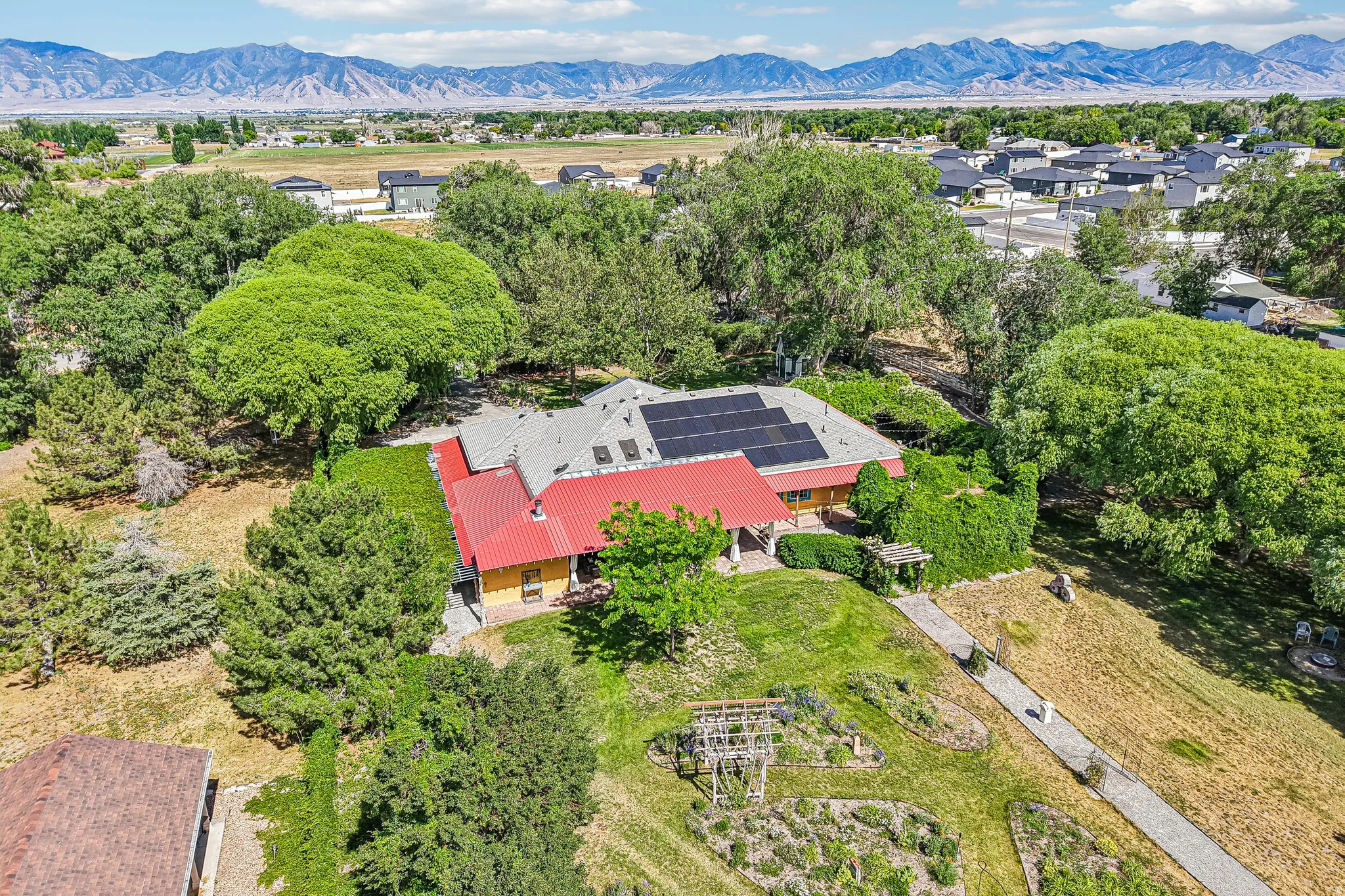 Expansive property featuring a red metal roof, solar panels, and mature landscaping